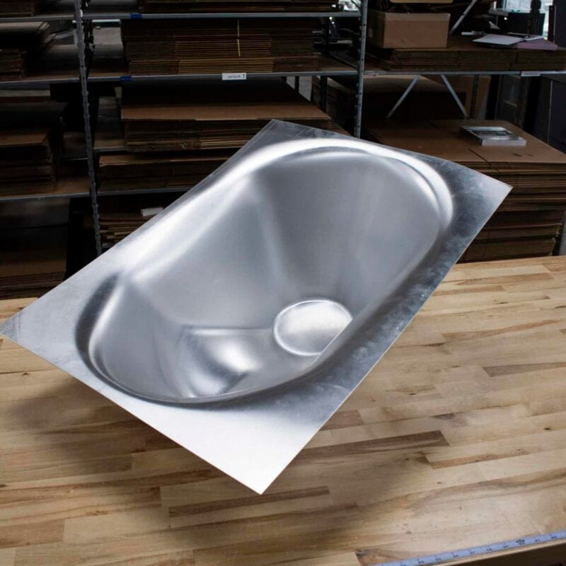 Deep-drawn stainless steel basin formed from a flat sheet without hard tooling