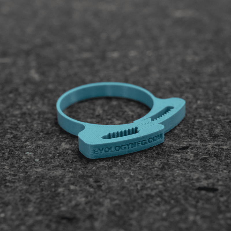 Teal FDM-printed hose clamp with embossed lettering on a textured surface