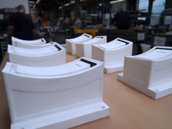 Row of white SLS-printed nylon equipment housings on a workbench
