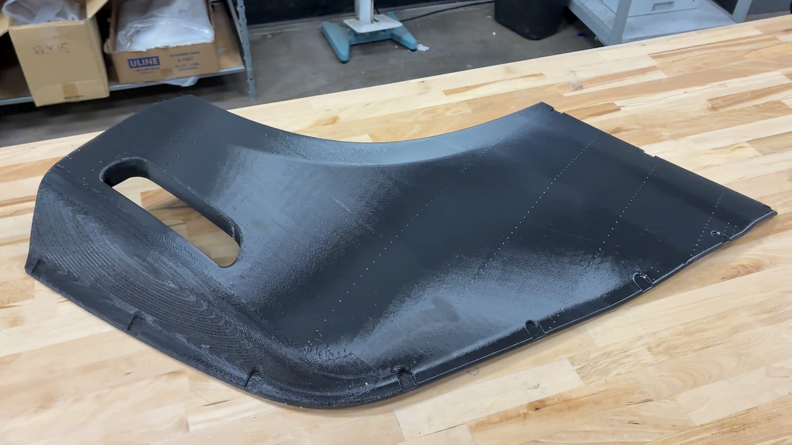 A large curved black FDM-printed ASA mold panel with a cutout, resting on a workbench