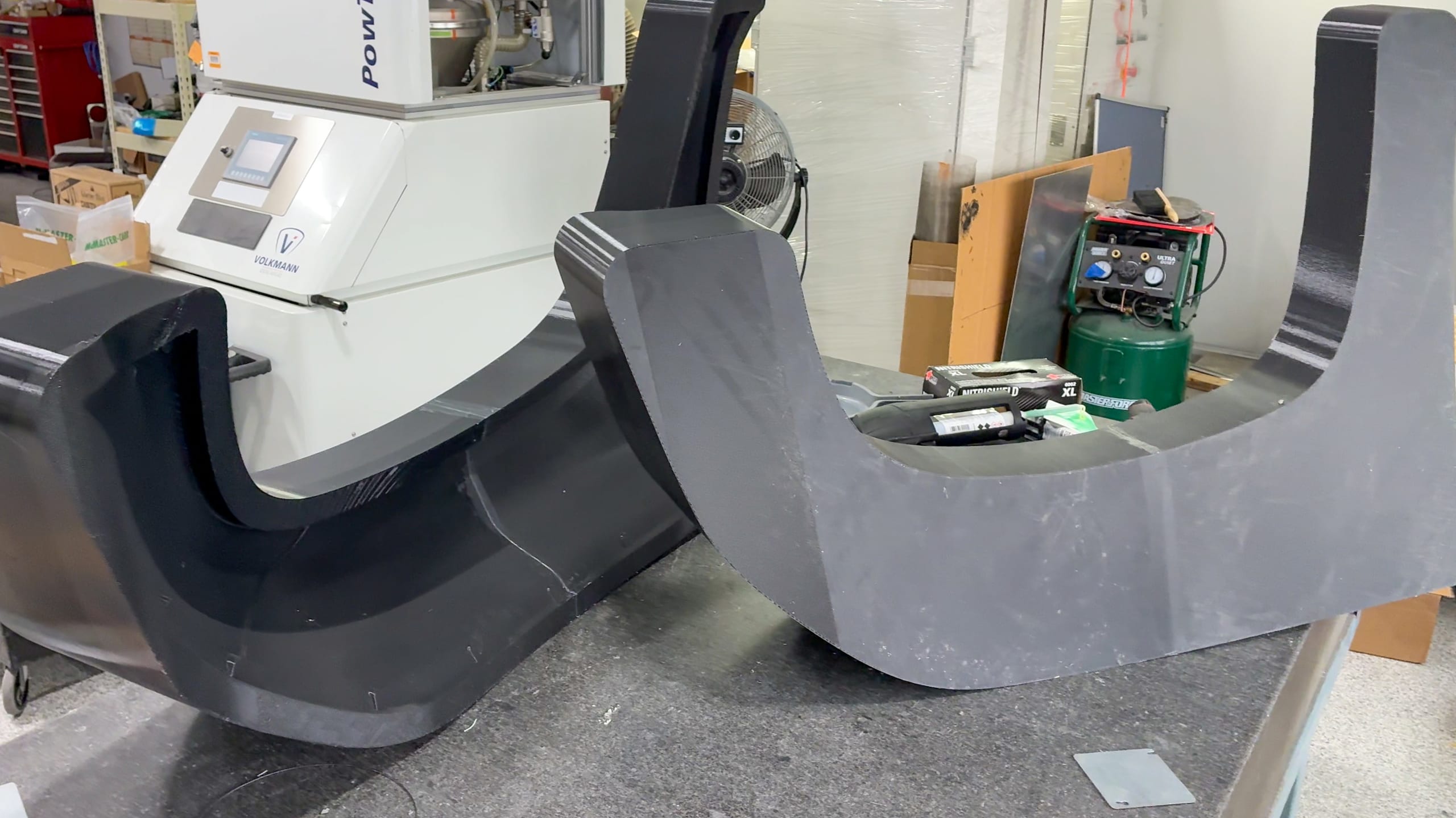Two segmented U-shaped ASA mold sections staged near a Volkmann powder system before bonding