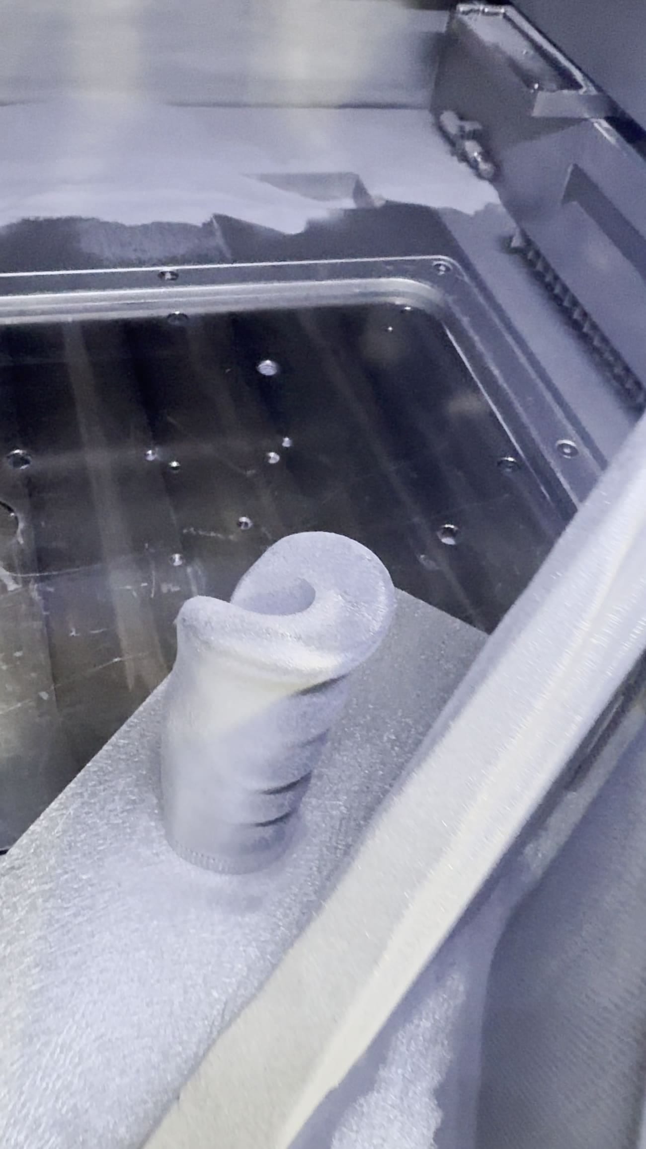 A printed part sitting in the powder bed inside the EOS machine