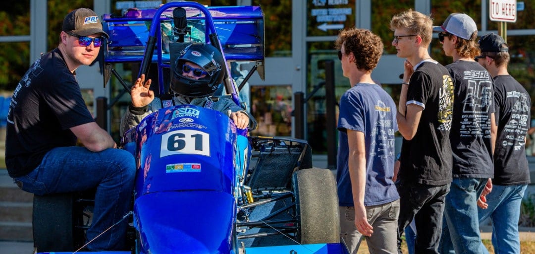 Pioneer Racing students with their blue PR25 Formula SAE car