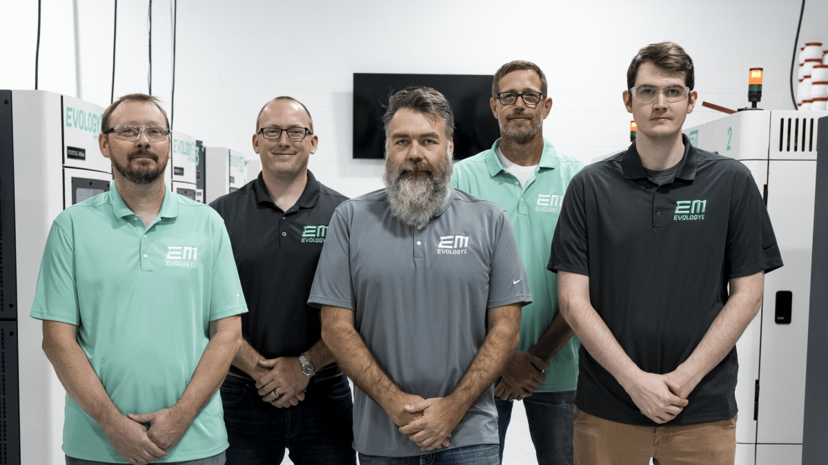 The Evology Manufacturing team standing together in front of additive manufacturing equipment